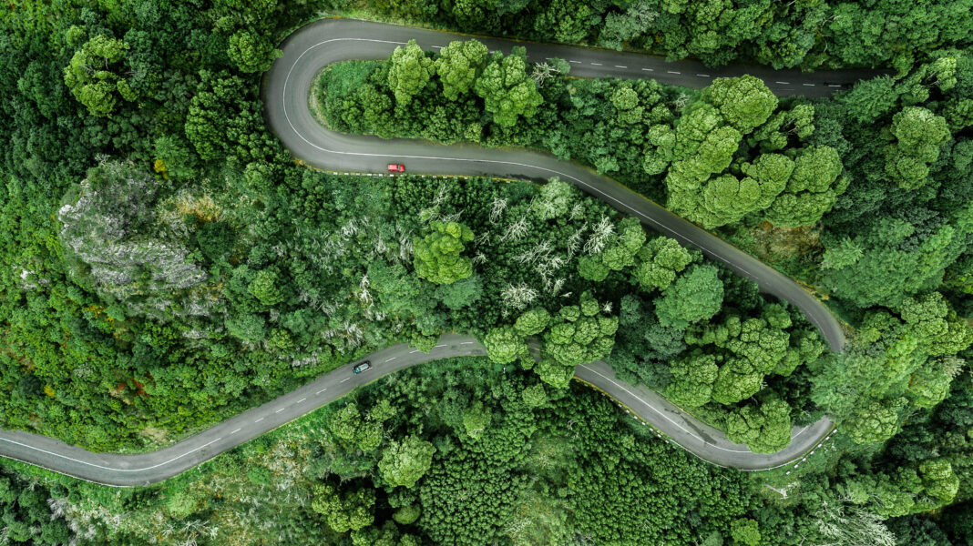 Aerial view of winding road trough the dense woods on the high mountain.